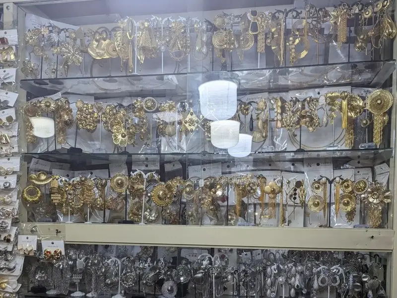 Gold-tone and silver-tone statement earrings and bridal jewellery sets in a display case at Tejuosho Market